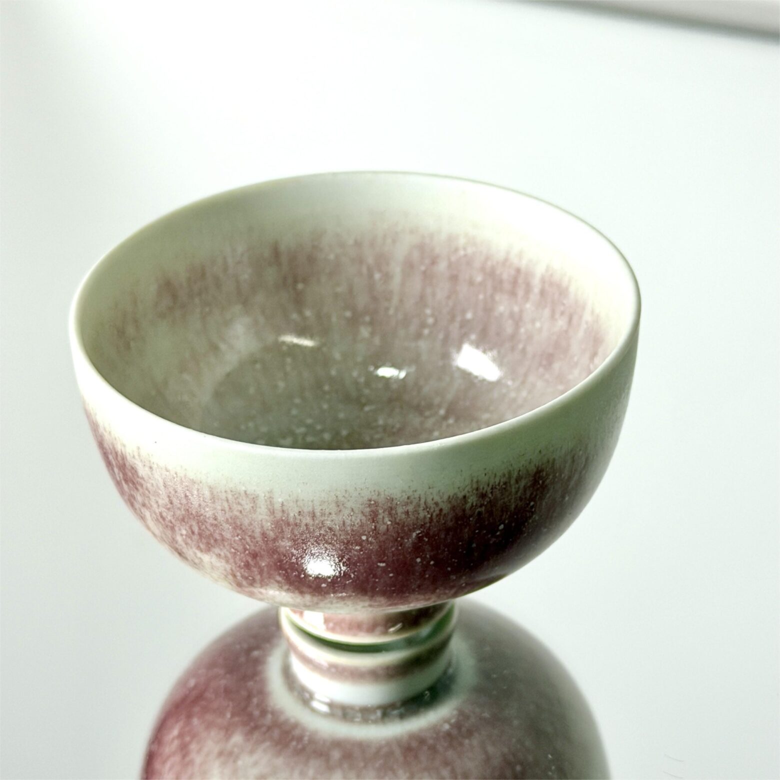 handmade tea cup from Yunnan side view, soft pink and white kiln glaze, small footed cup around 5cm tall